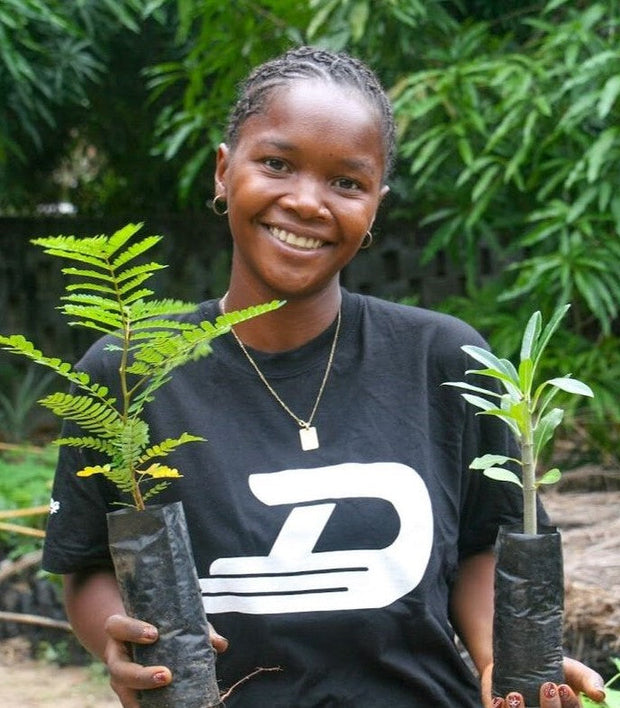 A Young Lady in Madagascar holding tree saplings which are planted by Ecologi, when you place an order with State of Disarray