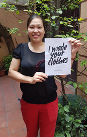 Fair Trade image. State of Disarray tailor Mrs Thuy holding a poster by Fashion Revolution 
