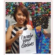 Mrs Linh A State of Disarray Tailor holding a Fashion Revolution poster. 